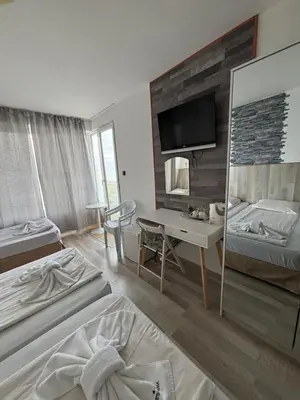 a room with two beds and a desk and a television at Свети Никола in Sozopol