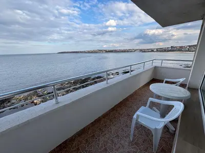 a table and a stool on a balcony overlooking the water at Свети Никола in Sozopol