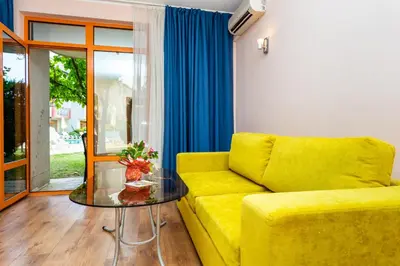 a yellow couch in a living room with a glass table at Complex Sunrise by HMG - All Inclusive in Sunny Beach