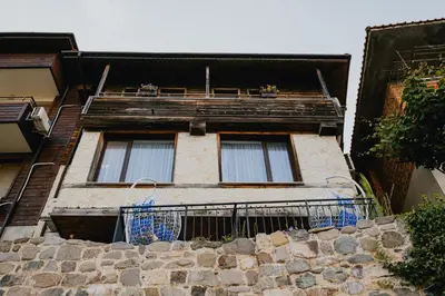 a building with a balcony on top of a stone wall at Miletia Suites in Sozopol
