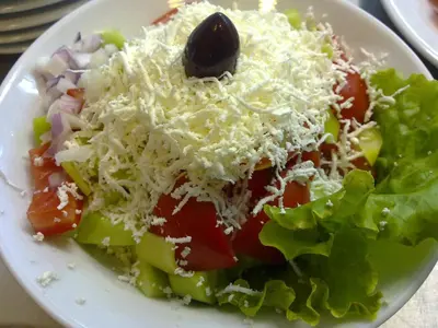 a white plate with a salad with cheese and vegetables at Family Hotel Eliri in Nesebar