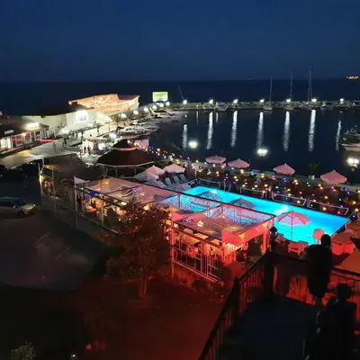 a view of a restaurant with a pool at night at Apartment Marina Dinevi View in Sveti Vlas