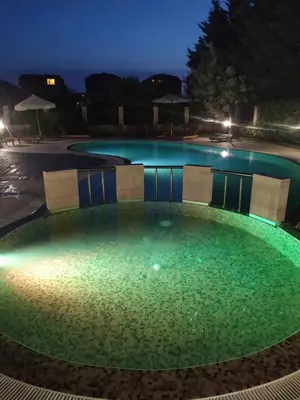 a swimming pool with green water at night at Mellia Boutique Apartments in Ravda