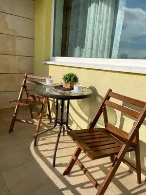 a table and chairs on a balcony with a window at Апартамент Бриз 16 in Sunny Beach