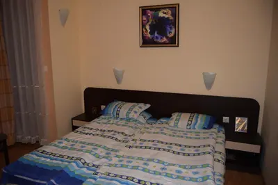 a bed with a blue and white comforter and two pillows at Paradise Bay Villas in Sozopol