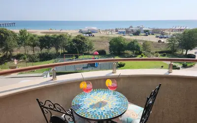 a table on a balcony with a view of the beach at Golden Sunrise in Shkorpilovtsi
