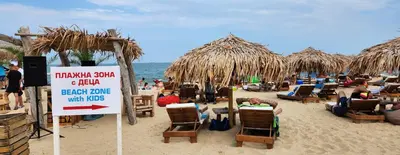 a beach with chairs and umbrellas and a sign at Golden Sunrise in Shkorpilovtsi
