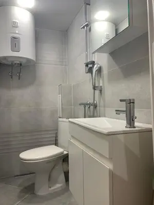 a white bathroom with a toilet and a sink at Апартамент за гости in Varna City