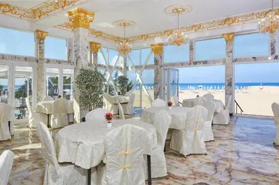 a restaurant with white tables and chairs and the beach at Hotel Amore Beach - All Inclusive in Elenite