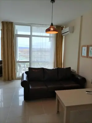 a living room with a leather couch and a window at Sun City Apartments in Sunny Beach