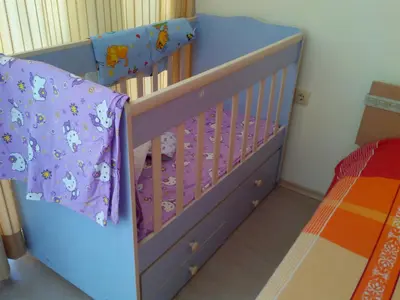 a blue crib in a room with a bed at Sun City Apartments in Sunny Beach