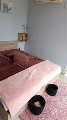 a bedroom with a bed with a pink blanket and a rug at Sun City Apartments in Sunny Beach
