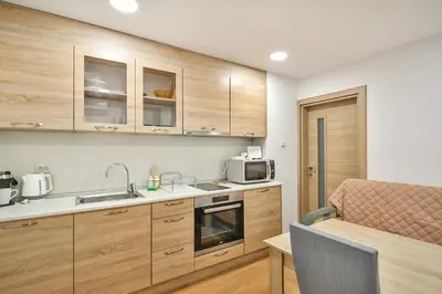a kitchen with wooden cabinets and a sink and a microwave at Hideout in heart of Varna with WiFi in Varna City