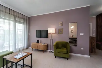 a living room with a green chair and a television at Smokinia Sunrise - Kavatsi Beach, Sozopol in Sozopol