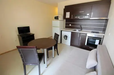 a small room with a table and a kitchen at Menada Green Hills Apartments in Sozopol
