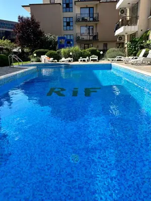 a large blue swimming pool in front of a building at Голям апартамент с прекрасна гледка кьм морето in Ravda