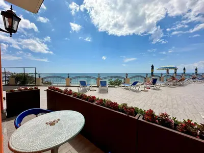 a patio with a table and chairs and the ocean at Apartment complex Mirage of Nessebar in Nesebar