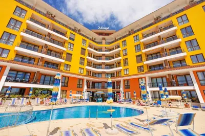 a large building with a pool and lounge chairs at Apartment complex Mirage of Nessebar in Nesebar