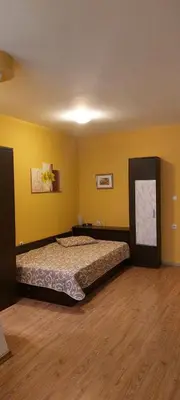 a bedroom with a bed in a room with yellow walls at Илеа апартамент in Burgas City