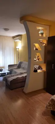 a bedroom with a bed and a wall with shelves at Илеа апартамент in Burgas City