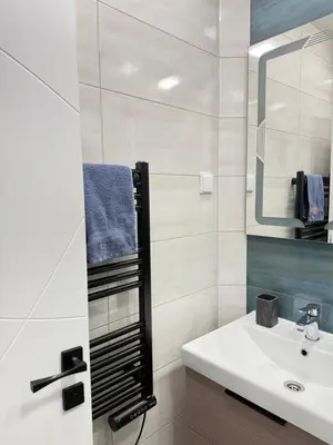 a white bathroom with a sink and a mirror at Varna Cathedral Boutique Apartment in Varna City