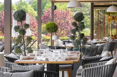 a dining room with tables and chairs and flowers at Санта Марина-Сладка къща in Sozopol