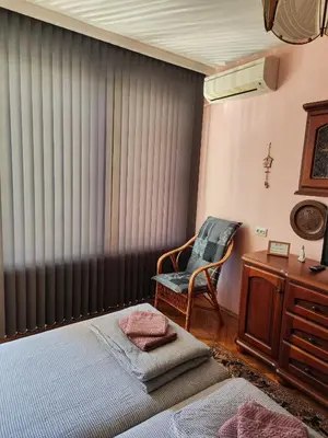 a bedroom with a bed and a chair and a window at Сладкият кът на Радост in Burgas City