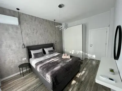 a bedroom with a large bed and a table at Vanquish Central Apartment in Varna City