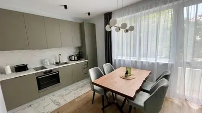 a kitchen and dining room with a wooden table and chairs at Vanquish Central Apartment in Varna City