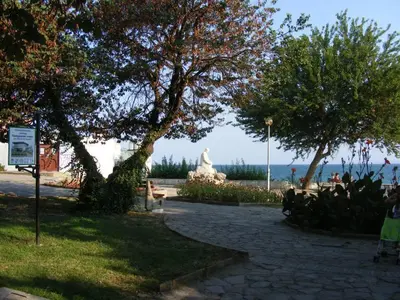 a park with a statue and the ocean in the background at Family Hotel Electra in Pomorie
