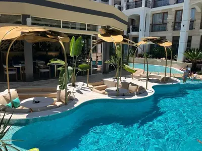 a pool with umbrellas and chairs and a building at Apartament Harmony in Sunny Beach