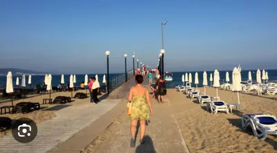 a woman walking down a sidewalk on the beach at Studio 39 in Sunny Beach