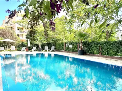 a blue swimming pool with chairs and trees at Villa Aria - Menada Apartments in Sunny Beach