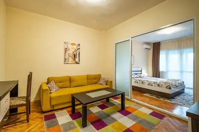 a living room with a yellow couch and a bedroom at Primorski 2bdrm Central Apartment in Varna City