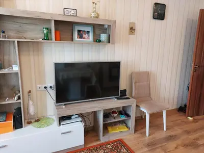 a living room with a television and a chair at Прекраснные апартаменты с панорамным видом на море in Byala