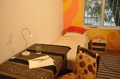 a small room with a bed and a table with a lamp at Arlequin Apartment in Varna City