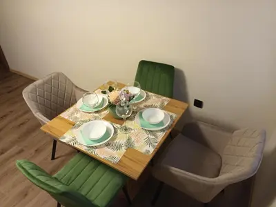 a dining room table with green chairs and a table with plates at ToP center of Varna in Varna City