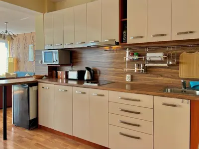 a kitchen with white cabinets and a wooden wall at Beachfront Havana in Sveti Vlas