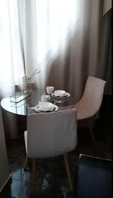 a dining room table with a white chair and a table with dishes on it at Central Apartment 5min to beach in Varna City