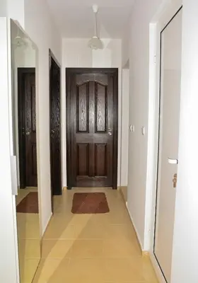 a hallway with a wooden door and a tile floor at DDenko Apartment in Burgas City