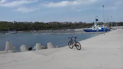 a bike parked on a sidewalk next to a body of water at DDenko Apartment in Burgas City
