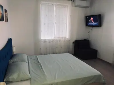 a bedroom with a bed and a window and a television at Bluemoon-Apartment with Parking in Burgas City