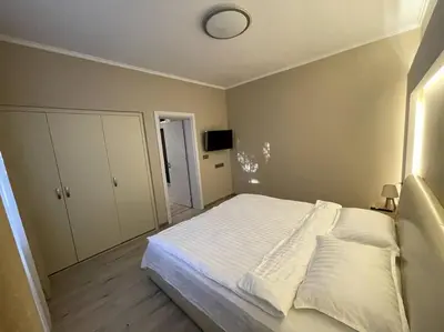 a bedroom with a white bed and a clock on the wall at City Center Apartment 1 in Varna City