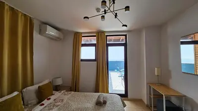 a bedroom with a bed and a large window at Квартира с потрясающим видом in Sveti Vlas