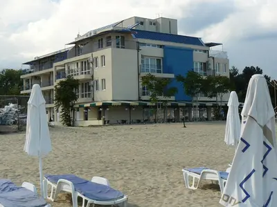a building on the beach with chairs and umbrellas at Hotel Star in Sunny Beach