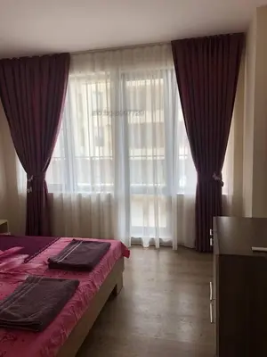 a bedroom with a bed with red sheets and large windows at Комплекс Рич 2 in Ravda