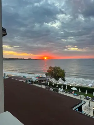a sunset over a beach with umbrellas and the ocean at Комплекс Рич 2 in Ravda