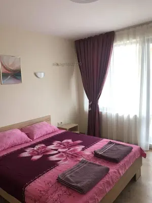 a bedroom with a pink bed with towels on it at Комплекс Рич 2 in Ravda