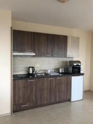 a kitchen with wooden cabinets and a sink and a refrigerator at Комплекс Рич 2 in Ravda