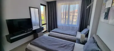 a hotel room with two beds and a flat screen tv at Balcony Bliss: The Black Sea Pearl in Sveti Vlas